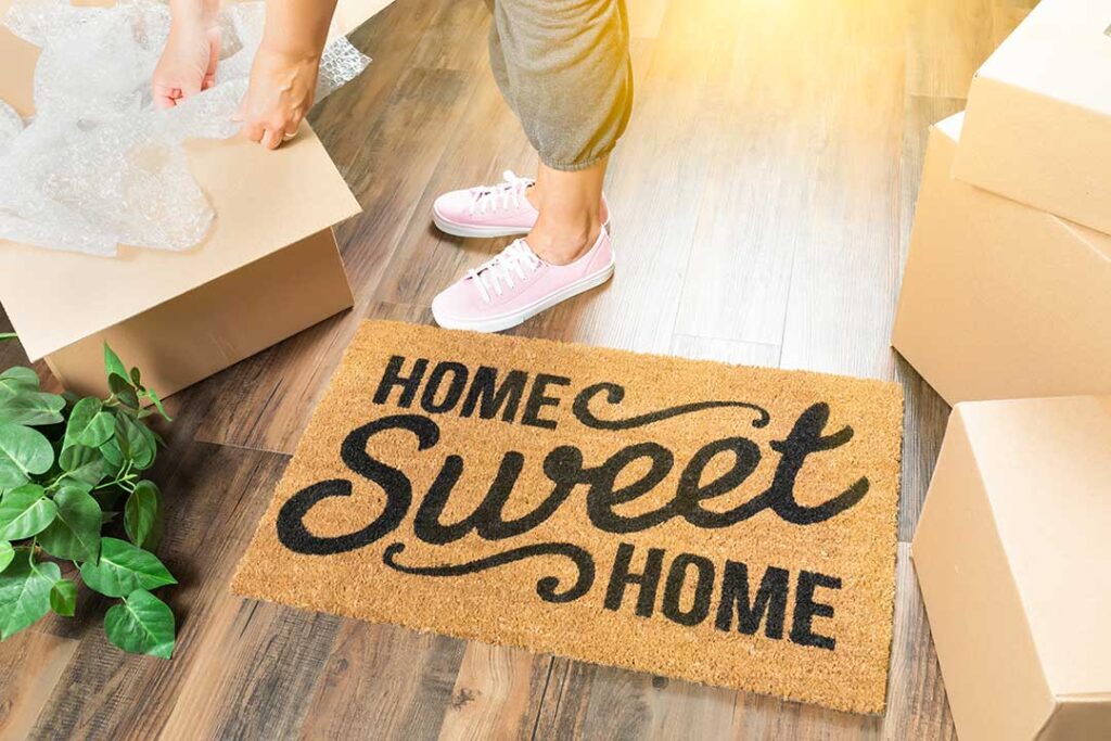 Homeowner arranging neutral furniture and clearing clutter in a bright living room.